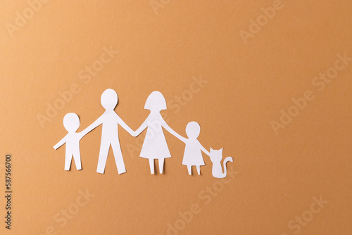 White paper cut out of family with two children and ca and copy space on brown background