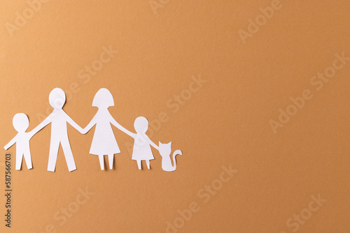 White paper cut out of family with two children and ca and copy space on brown background