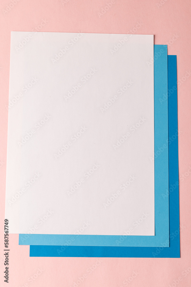 Close up of white and blue paper on pink background with copy space