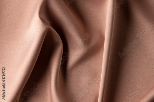 Close up of plain beige satin fabric with folds, copy space