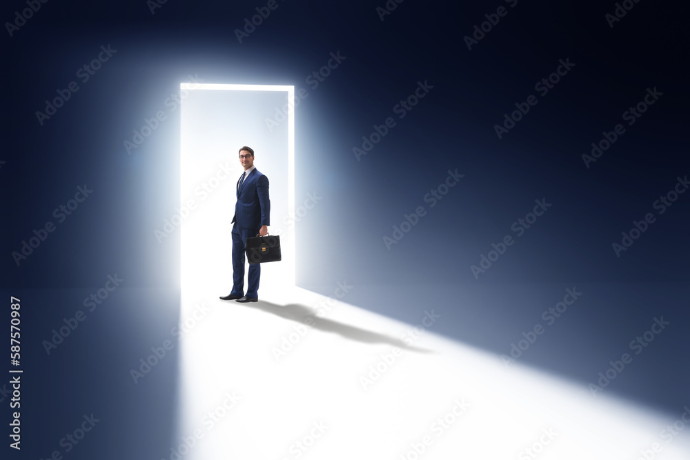 Fototapeta premium Businessman entering backlit door in escape concept