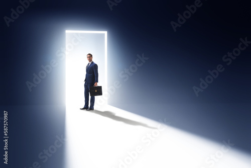 Businessman entering backlit door in escape concept