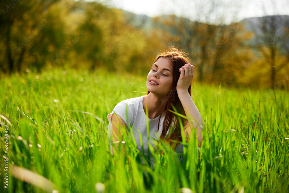 portrait of a pensive redhead woman sitting in the grass at sunset portrait of a pensive redhead woman sitting in the grass at sunset