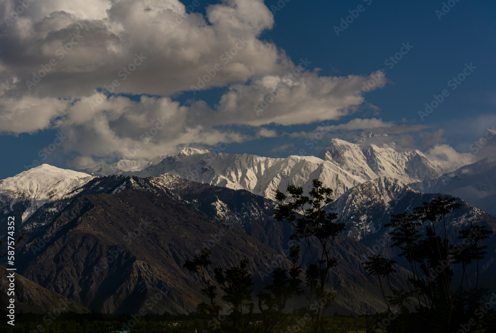 beautiful sunset over snow mountains with clouds and blue sky , snow mountains in golden light during sunset 