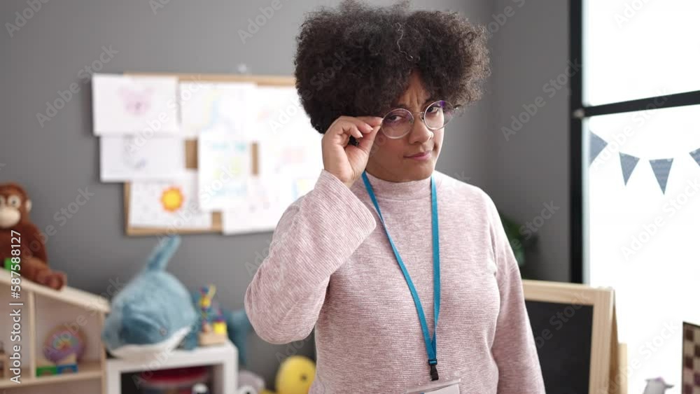 Young african american woman preschool teacher saying no with finger at kindergarten