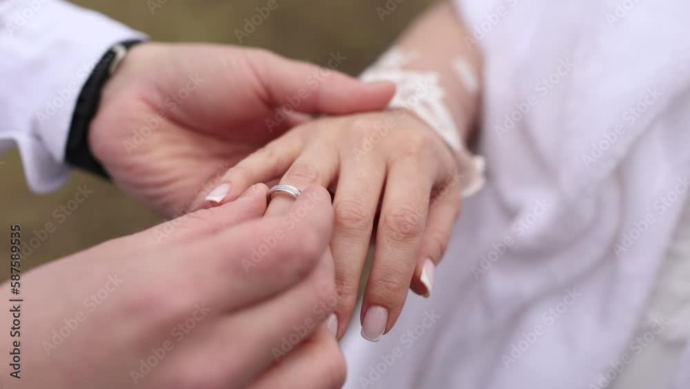 the groom puts a golden wedding ring on the bride's hand the groom puts a golden wedding ring on the bride's hand