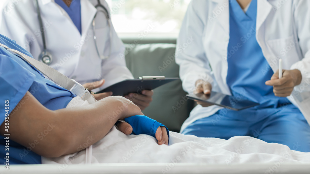 Cropped image of doctor in uniform with stethoscope using tablet standing in hospital with patient lying in bed on background Operator checks patient information on digital tablet Cropped image of doctor in uniform with stethoscope using tablet standing in hospital with patient lying in bed on background Operator checks patient information on digital tablet