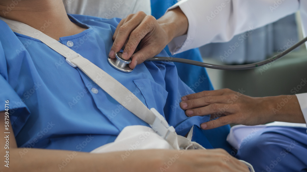 Cropped image of doctor in uniform with stethoscope using tablet standing in hospital with patient lying in bed on background Operator checks patient information on digital tablet Cropped image of doctor in uniform with stethoscope using tablet standing in hospital with patient lying in bed on background Operator checks patient information on digital tablet