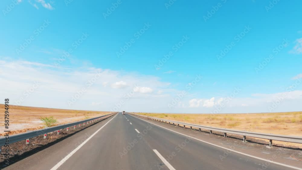 4K view of asphalt road passing through desert near Khavda village in Kutch, Gujarat, India. Travel to Rann of Kutch. Road trip on Desert road with clouds in blue sky. Vehicle passing on empty road. 4K view of asphalt road passing through desert near Khavda village in Kutch, Gujarat, India. Travel to Rann of Kutch. Road trip on Desert road with clouds in blue sky. Vehicle passing on empty road.