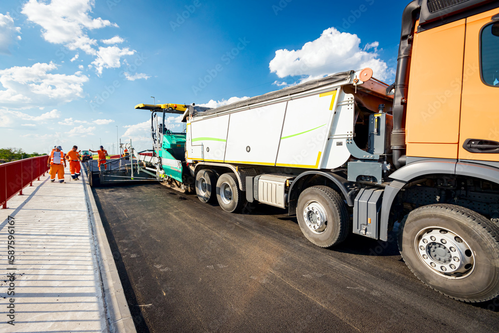 Truck is loading hot asphalt into spreader, tarmac road laying spreader machine Truck is loading hot asphalt into spreader, tarmac road laying spreader machine