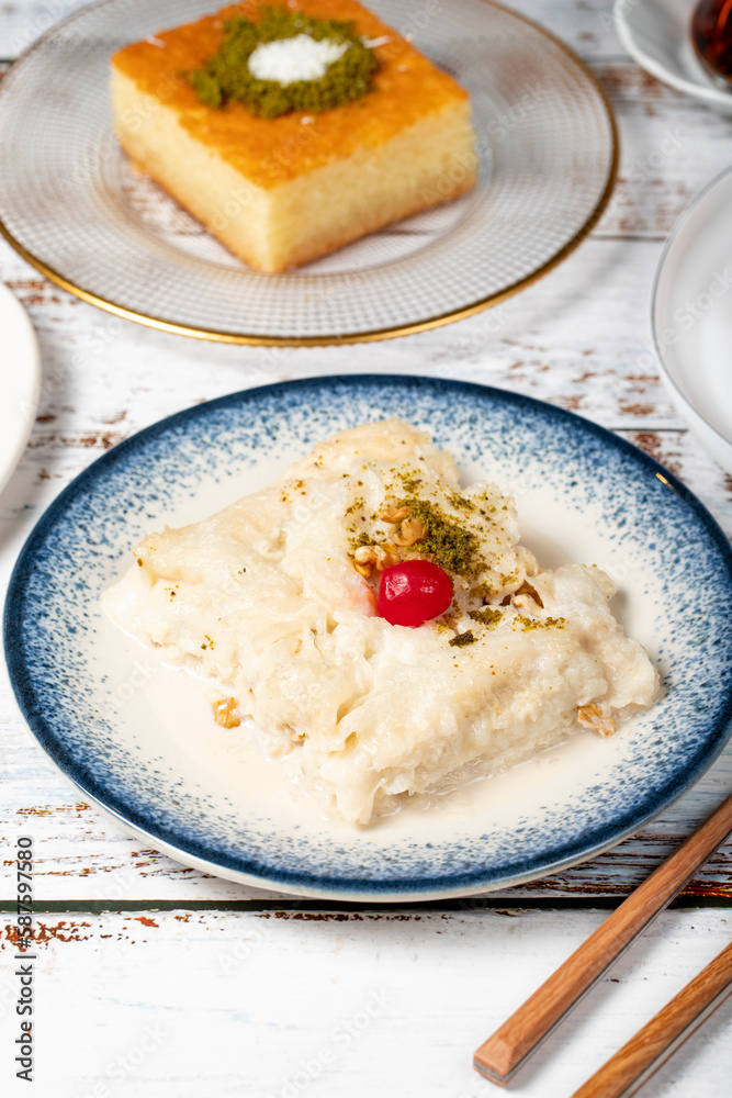Güllaç, revani, tulumba and bread kadayif dessert with cream on a wood floor. Ramadan sweets. Traditional Turkish cuisine delicacies Güllaç, revani, tulumba and bread kadayif dessert with cream on a wood floor. Ramadan sweets. Traditional Turkish cuisine delicacies