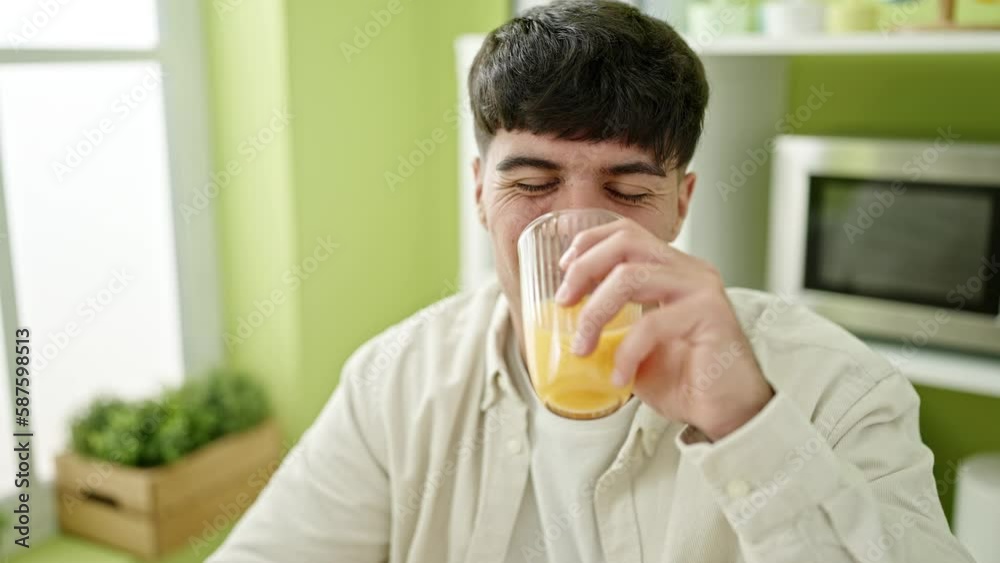 Young hispanic man drinking orange juice speaking at dinning room Young hispanic man drinking orange juice speaking at dinning room