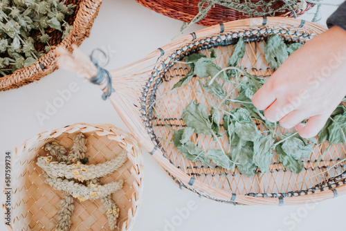 Shot from above of medicinal herbs drying in woven baskets on a white background.
