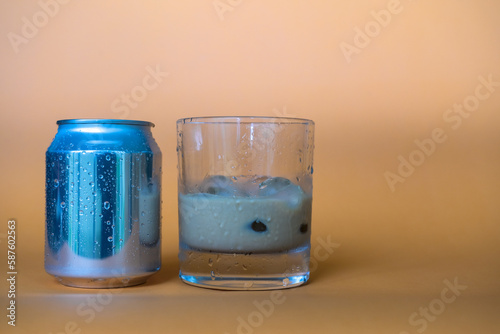 Glass of fresh cold chocolate drink sitting next to its can over blurry background