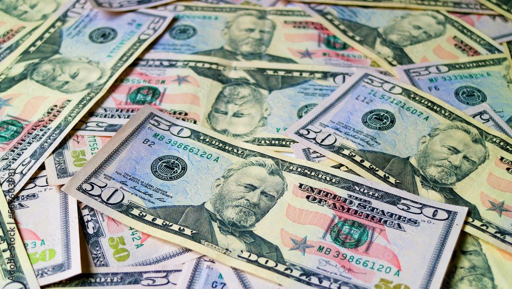 Heap of United States fifty dollar bills with selective focus and blurred background