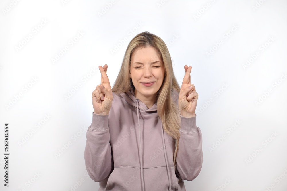 Young woman smiling while posing with fingers crossed for good luck 
