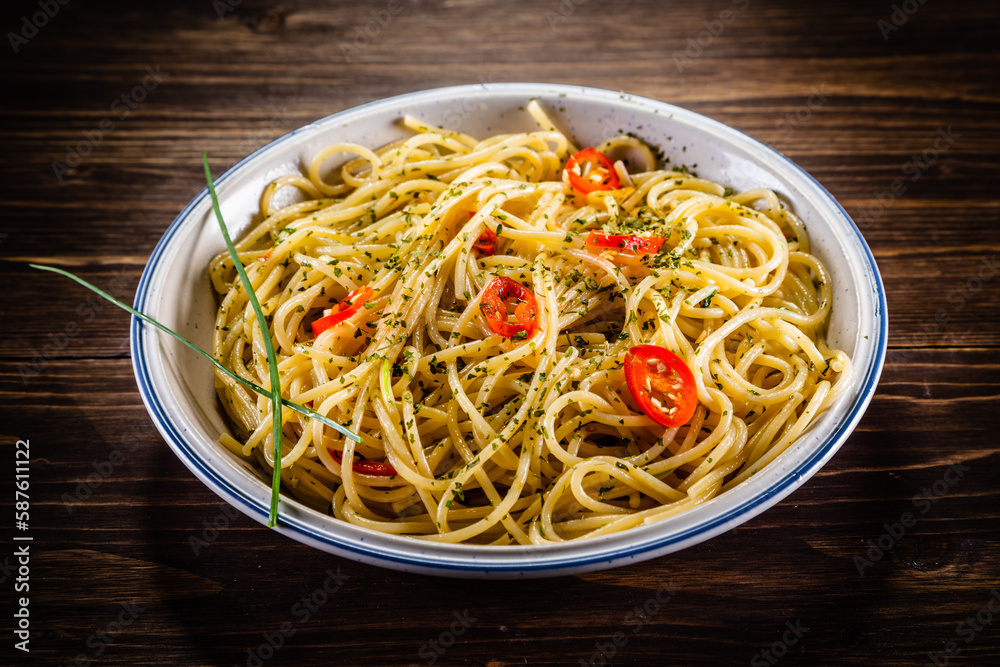 Spaghetti with chili and olive oil on wooden background