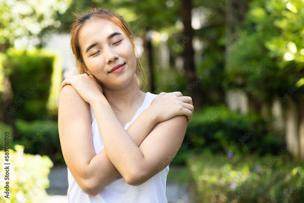 Happy smiling fitness woman self hugs for self caring in summer green city environment with refreshing clean air Happy smiling fitness woman self hugs for self caring in summer green city environment with refreshing clean air