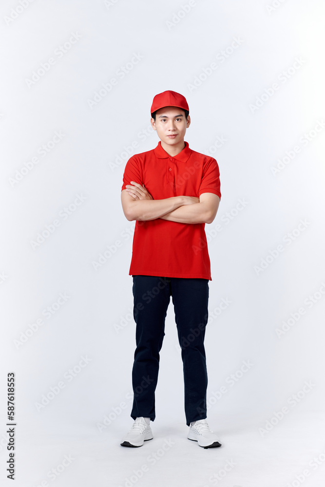 Smiling delivery man in red uniform standing with arm crossed - isolated on white background Smiling delivery man in red uniform standing with arm crossed - isolated on white background