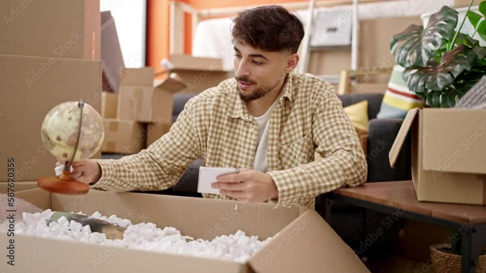 Young arab man unpacking cardboard box writing on notebook at new home Young arab man unpacking cardboard box writing on notebook at new home