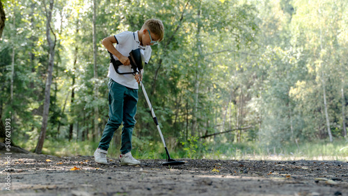 a boy with a metal detector in the park