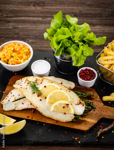 Photography Fish dish - fried fish fillet with green asparagus and vegetables served on blac