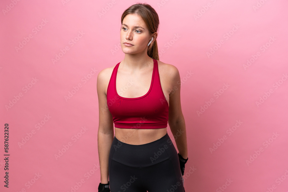 Young caucasian woman isolated on pink background stretching leg