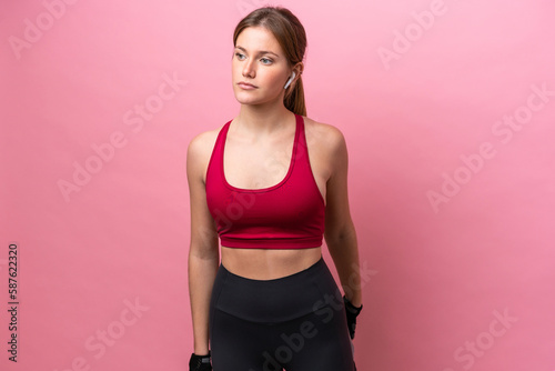 Young caucasian woman isolated on pink background stretching leg © luismolinero