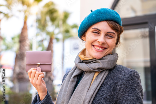 Brunette woman holding a wallet at outdoors smiling a lot © luismolinero