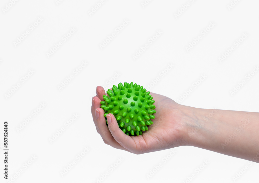 Zielona piłka z kolcami do rehabilitacji trzymana w dłoni na białym tle - obrazy, fototapety, plakaty 