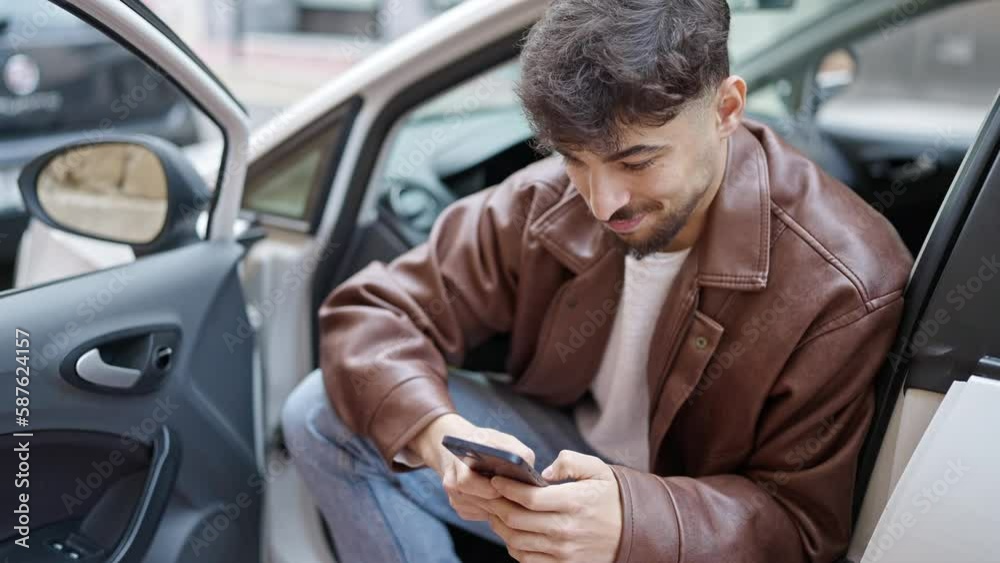 Young arab man using smartphone sitting on car at street Young arab man using smartphone sitting on car at street
