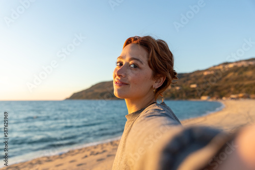 redhead woman taking a selfie on the beach