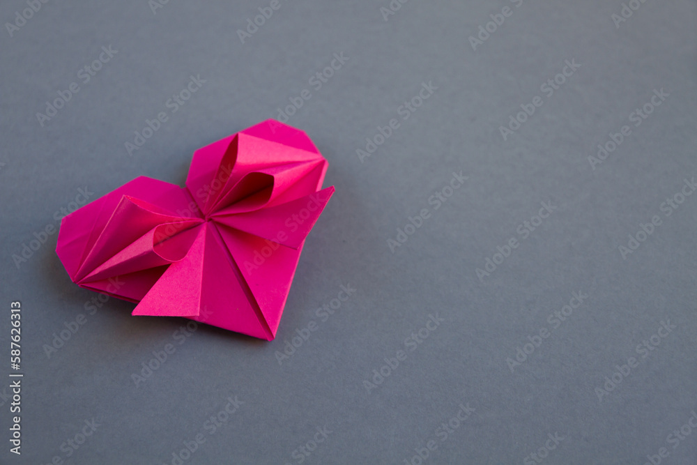 pink paper heart origami isolated on a grey background pink paper heart origami isolated on a grey background