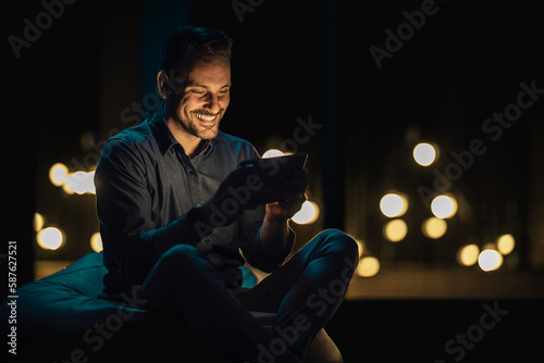 Young businessman sitting in bag chair and using digital tablet after successfull day on work