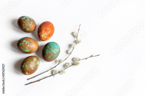 Easter composition of colored chicken eggs and twigs of pussy willow on a white background