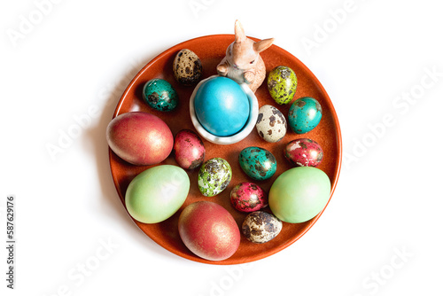A red plate with an easter bunny and colored chicken eggs and quail eggs. Table top view