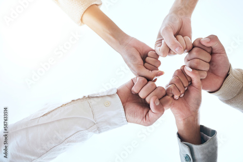Below business people, fist bump and circle for team building, support and group goals in workplace. Men, women and teamwork with solidarity for success, motivation and trust with diversity at job