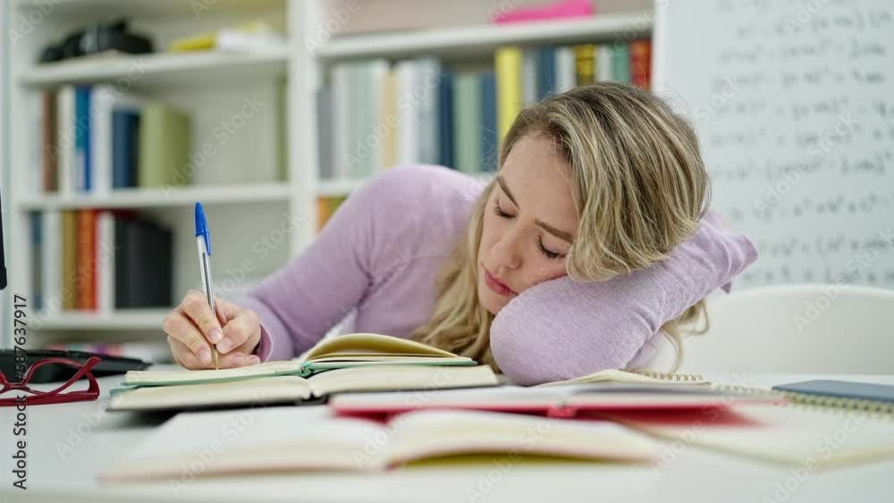 Young blonde woman student writing notes sleeping at classroom Young blonde woman student writing notes sleeping at classroom