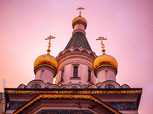 Oppression of Christians and sectarian strife concept. Golden domes of russian Church of St. Nicholas the Wonderworker at dawn isolated in the golden hour