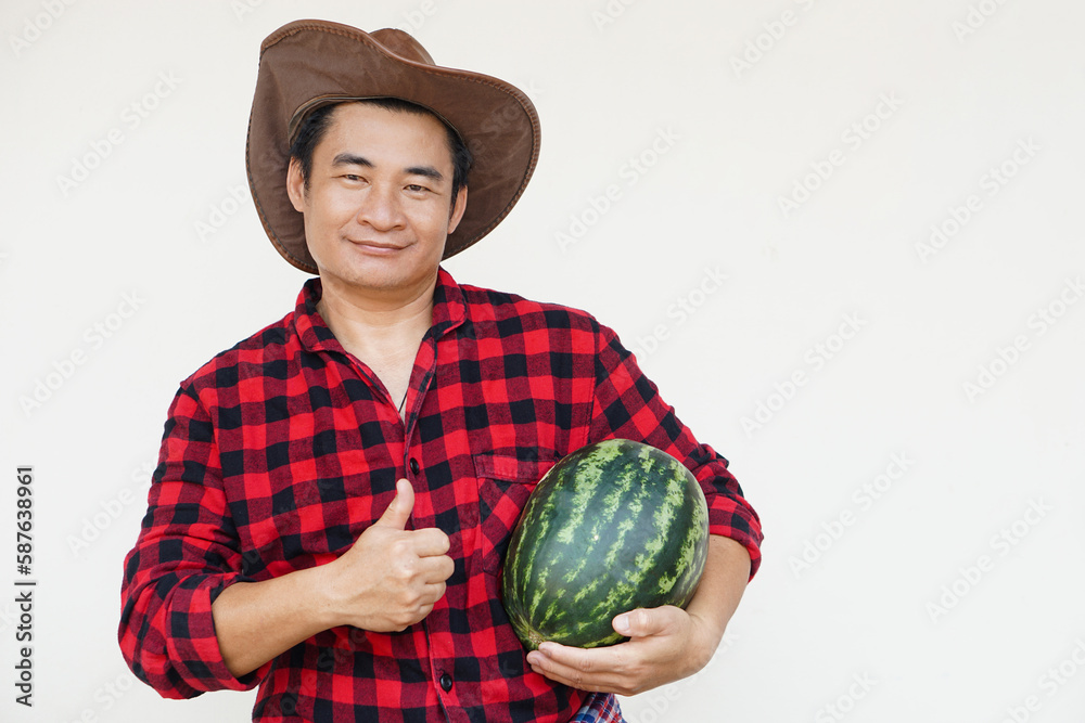 Handsome Asian man wears hat, red plaid shirt, holds watermelon fruit. Concept, Agriculture occupation, Thai farmer, grow and sell watermelon fruits as economic crop Handsome Asian man wears hat, red plaid shirt, holds watermelon fruit. Concept, Agriculture occupation, Thai farmer, grow and sell watermelon fruits as economic crop