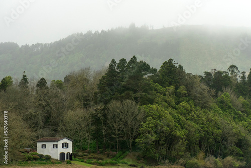 White house next to Lagoa das Sete Cidades, between trees and fog, on the island of São Miguel, Azores, Portugal.