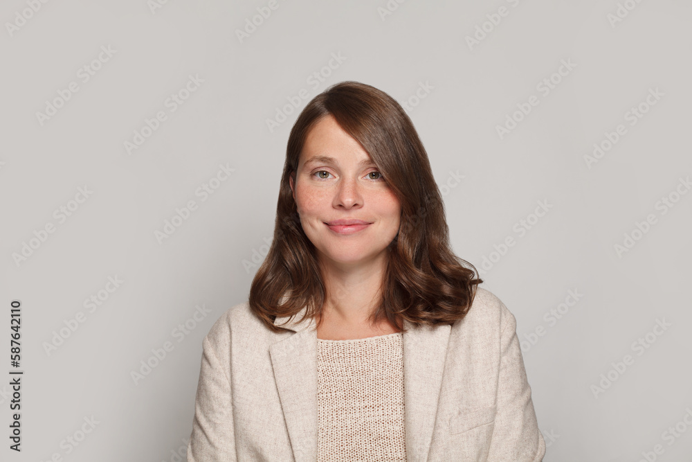 Obraz premium Studio portrait of smiling positive cheerful business woman in white casual suit