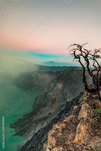 Sunrise over Kawah Ijen Volcano revealing acid turquoise lake and toxic sulfur gases and dead trees next to illegal mining operation, Java, Indonesia photo