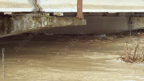 Floodwaters have risen all the way to top of bridge column. Thick big concrete pillars under water. An incredibly fast raging river. flow of a dangerous river. Slow motion photo