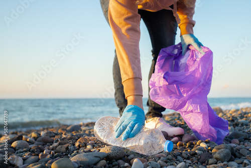 beach cleaning, woman collects plastic garbage in a bag on the seashore, Volunteer clean up trash