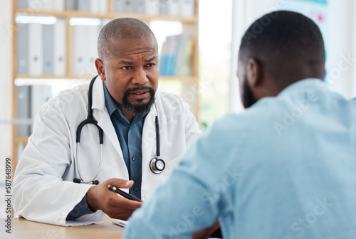 Doctor, serious black man and patient consultation in hospital for talking, checkup or results. Healthcare, medical professional and African person consulting physician for advice or cancer diagnosis