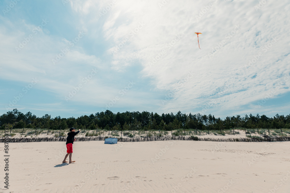 Obraz premium Boy flying kite on the beautiful sandy beach at Baltic Sea, Poland