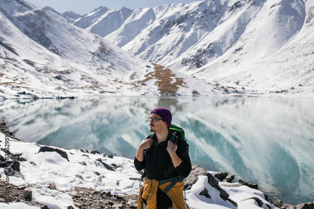 A medium shot photo of a man standing in front of a high mountain lake and looking in the direction A medium shot photo of a man standing in front of a high mountain lake and looking in the direction