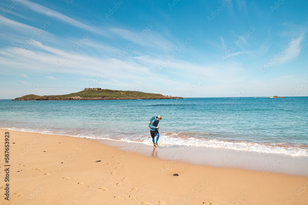 Young, passionate black-haired dobby runs from the waves of the Atlantic Ocean on a sandy beach near Porto Covo, Portugal. In the footsteps of Rota Vicentina