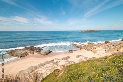 View of the Atlantic Ocean and its waves sending waves onto a sandy beach near Porto Covo  Western Portugal during a windless day. Fisherman trail  Rota Vicentina